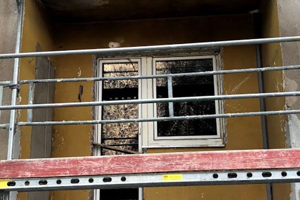 Bauarbeiten an einem Wohnhaus, Gerüst um ein Fenster herum aufgebaut, das eine Renovierung anzeigt.