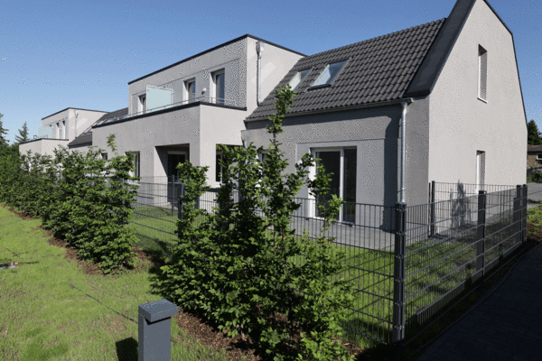 Ein Bild von modernen Reihenhäusern mit gepflegten Vorgärten, das die Wohnqualität in neuen städtischen Entwicklungen betont.