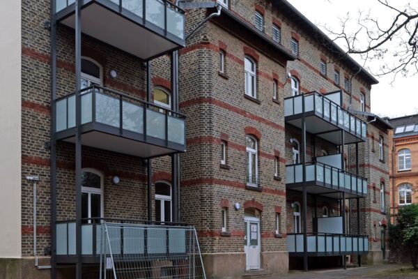 Altbau mit neuen, modernen Balkonen, die harmonisch mit der historischen Ziegelfassade kombiniert sind.