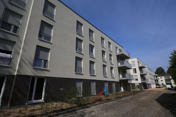 Ansicht einer modernen Wohnanlage, die durch ihre gleichmäßige und strukturierte Fassadengestaltung besticht.