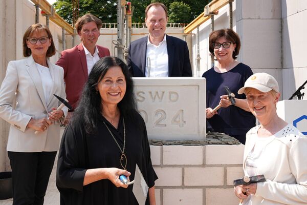 Grundsteinlegung für ein neues Bauprojekt in Düsseldorf, mit Bauherren und Architekten, die symbolisch den Grundstein setzen.