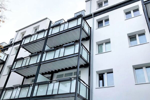 Schlankes, mehrstöckiges Wohngebäude mit markanten externen Treppen und verglasten Balkonen, das zeitgenössisches architektonisches Design in einem städtischen Umfeld hervorhebt.