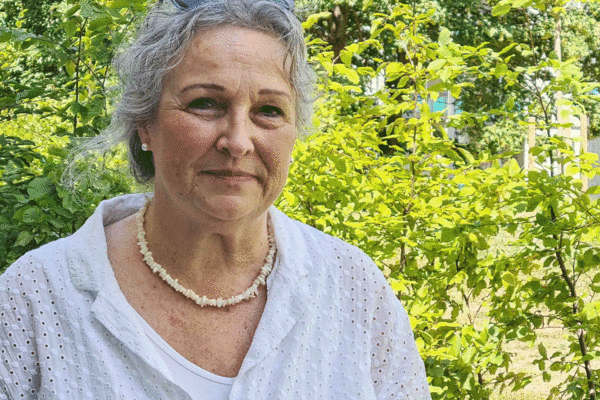 Ein natürliches Porträt einer älteren Frau im Garten, das Ruhe und Lebenserfahrung ausstrahlt.