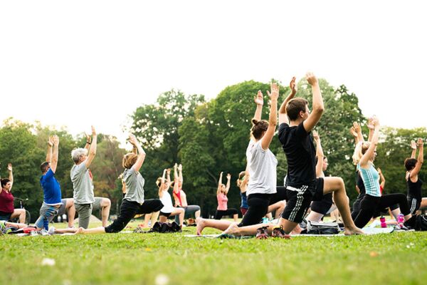 Eine Gruppe von Menschen macht gemeinsam Yoga in einem Park, eine friedliche Szene mit Fokus auf Gesundheit und Gemeinschaft.