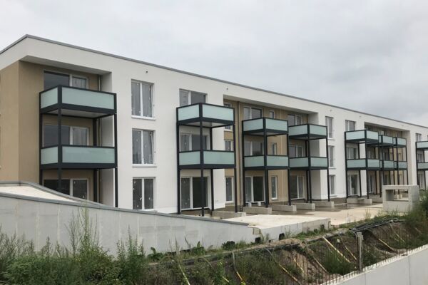 Ein modernes Wohngebäude mit mehreren Balkonen und hellen Fassadenfarben, ideal für städtisches Wohnen.