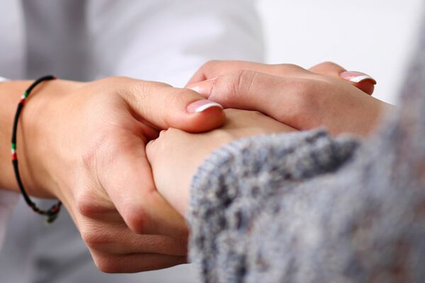 Eine Nahaufnahme, die zeigt, wie eine Person die Hand einer anderen hält, was Fürsorge und Unterstützung in menschlichen Beziehungen symbolisiert.