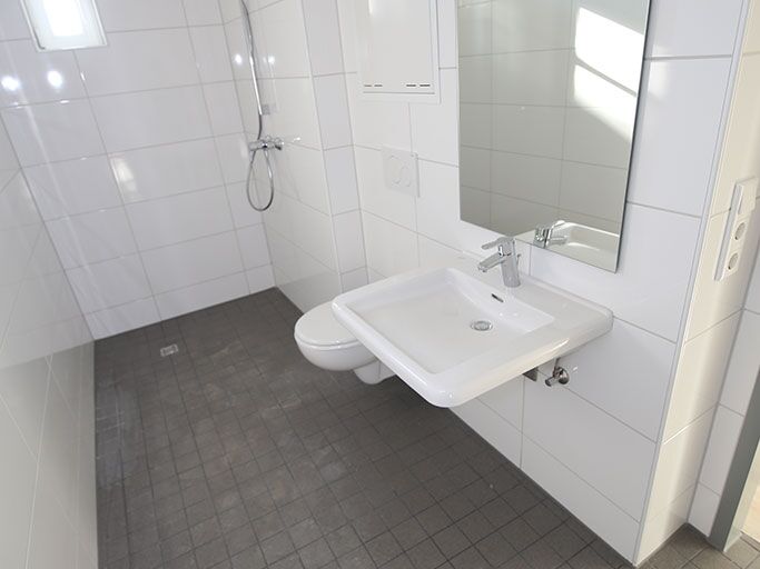 Bild eines kleinen, weißen Badezimmers mit einem Fenster, das den Raum natürlich beleuchtet.