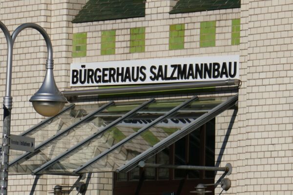 Der Eingangsbereich des Bürgerhauses Salzmannbau, markant mit Beschilderung und Architekturdetails.