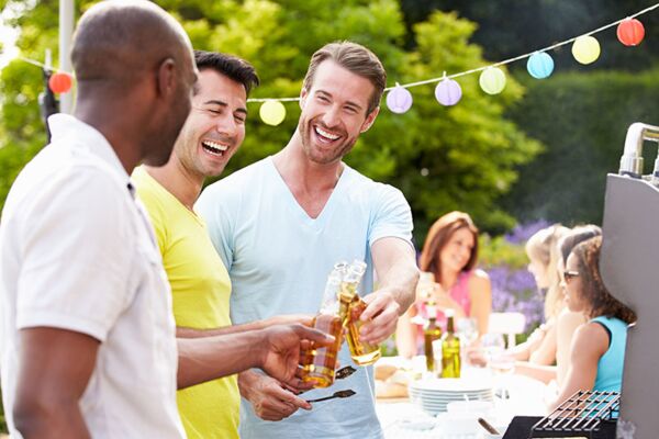 Ein fröhliches Beisammensein im Freien, bei dem drei Männer bei einer Grillparty auf dem Balkon sind.