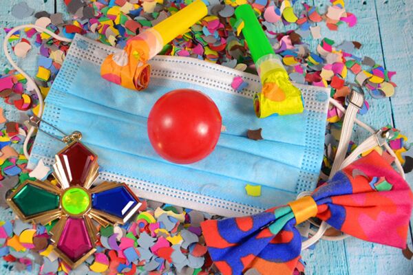 Eine lebendige Darstellung von Karnevalsutensilien und einer Gesichtsmaske, die die Balance zwischen Feier und Sicherheit während der COVID-19-Pandemie zeigt.