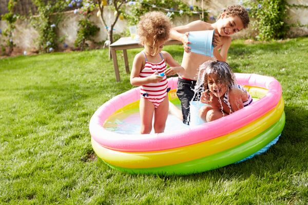 Ein sommerliches Bild von Kindern, die im Planschbecken spielen, verkörpert Freude und unbeschwerte Kindertage im Freien.