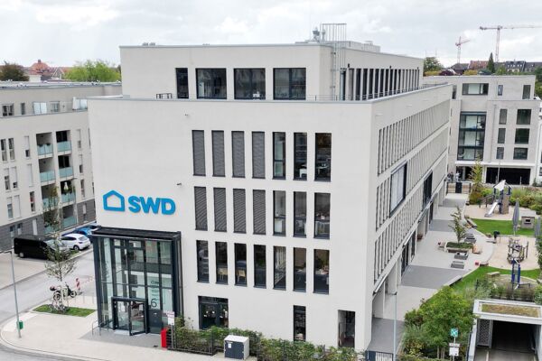 Ein modernes SWD-Gebäude mit klaren Linien, hellen Fassaden und einer integrierten Kindertagesstätte, gelegen in einer großzügigen, grünen Anlage.