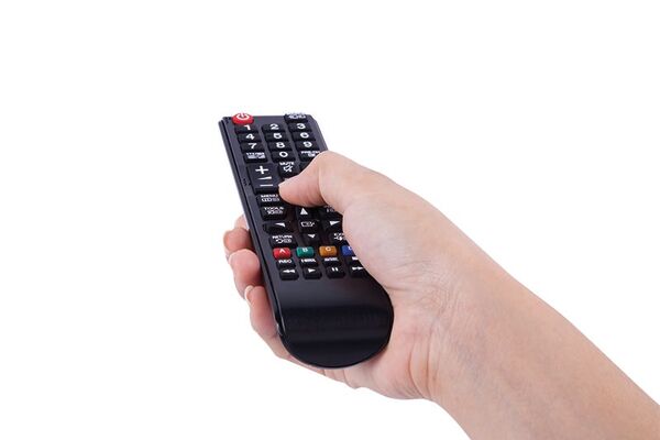 Nahaufnahme einer Hand, die eine TV-Fernbedienung hält. Symbolbild für Kabelfernsehen.