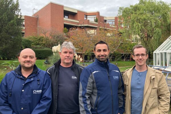 Ein Foto eines Teams von Stadtmitarbeitern in Düsseldorf, posierend in einer grünen Parkumgebung.