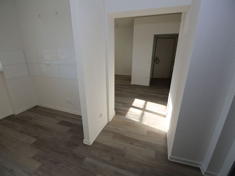 Leerer Raum mit Holzboden und einer Sicht auf eine geschlossene Zimmertür.