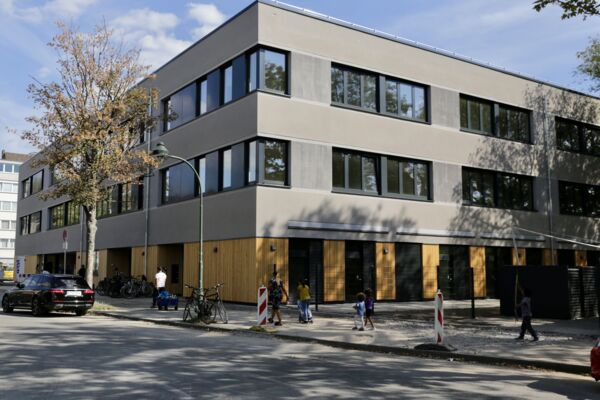 Eine Aufnahme eines modernen Schulgebäudes mit Kindern, die vor dem Eingang spielen, zeigt die Integration von Bildungsräumen in städtischen Umgebungen.