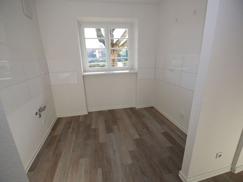 Innenraumfoto eines leeren Zimmers mit einem Fenster und einem Heizkörper an der Wand, das eine ruhige Atmosphäre zeigt.