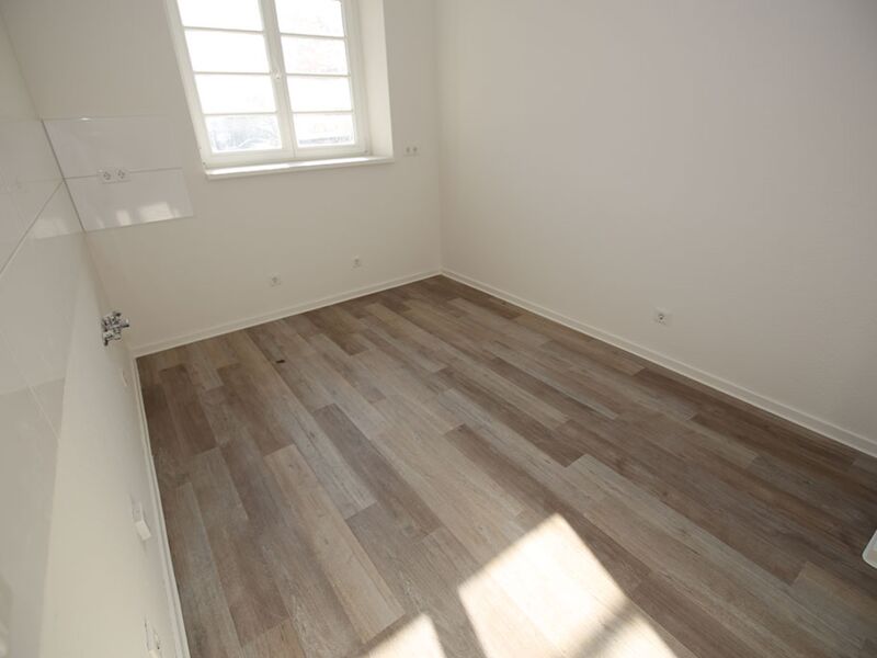 Helle, sonnenbeschienene Perspektive eines leeren Raumes mit Holzboden, gezeigt in einem minimalistischen Stil.