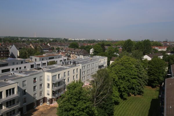 Luftaufnahme eines modernen Wohnkomplexes mit einer Ansammlung von Mehrfamilienhäusern und begrünten Innenhöfen.