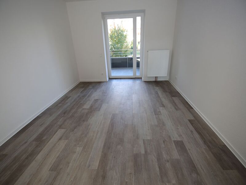 Fotografie eines leeren Zimmers mit Balkonzugang, ausgestattet mit einem Laminatboden.