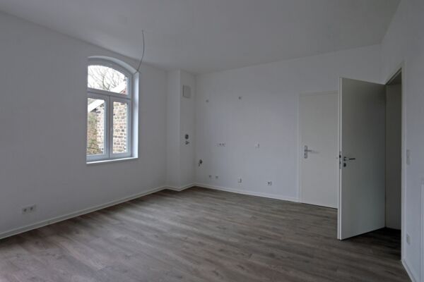 Helles, modern eingerichtetes Wohnzimmer mit Holzboden und großen Fenstern, die viel Tageslicht bieten.