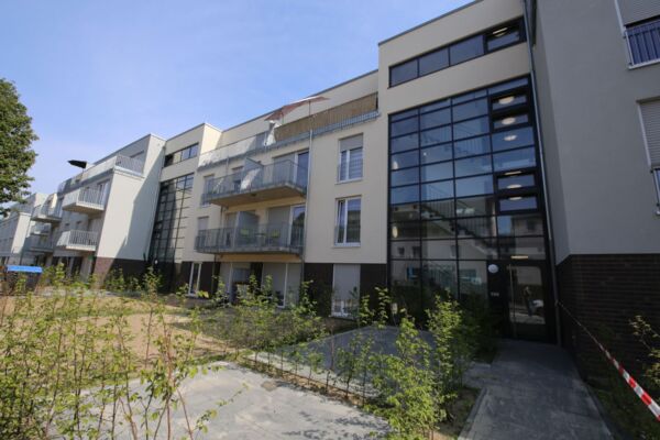 Ein neu entwickeltes Wohngebiet mit mehreren Mehrfamilienhäusern, die moderne Architektur und Balkone mit Blick auf angelegte Gärten zeigen.