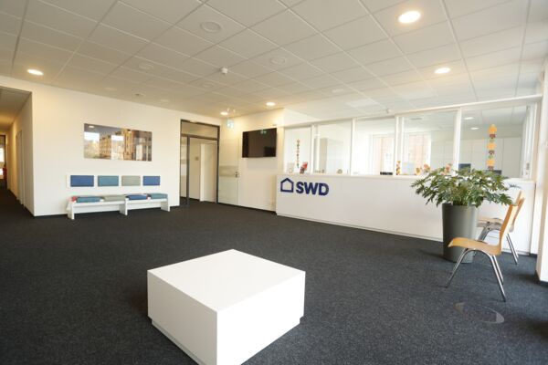 Empfangsbereich der SWD: Heller und einladender Empfangsbereich eines Unternehmensgebäudes mit moderner Inneneinrichtung und dem Firmenlogo prominent platziert.