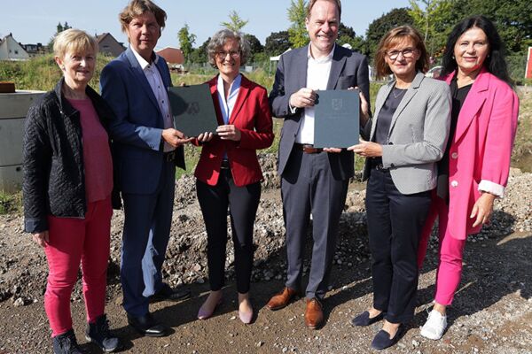 Offizielle Übergabe eines Förderbescheids an einem Baustellenstandort in Düsseldorf, mit Vertretern in festlicher Atmosphäre.