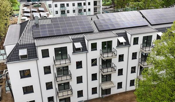 Ein neu errichtetes Gebäude mit einem umweltfreundlichen Solardach, das in einer ruhigen städtischen Umgebung steht. Das Design betont Nachhaltigkeit und moderne Wohnästhetik.