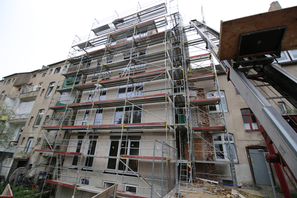 Renovierte Fassade in lebendiger Straße: Frisch renoviertes Wohngebäude in einer belebten städtischen Straße, das die gelungene Verbindung von alt und neu in der Stadtarchitektur darstellt.