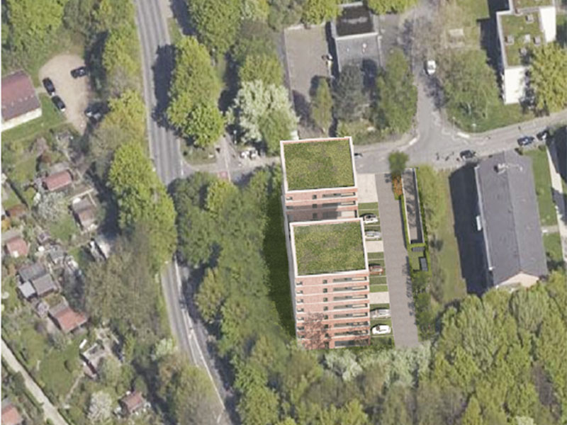 Drohnenaufnahme, die einen geplanten Wohnkomplex in einer grünen Umgebung zeigt, illustriert die Integration des neuen Gebäudes in die bestehende Landschaft und städtische Infrastruktur.