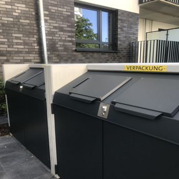 Moderne Abfallcontainer in einem Wohnkomplex, markiert für Verpackungsabfälle. Die Container sind in einem funktionalen und modernen Design gehalten.